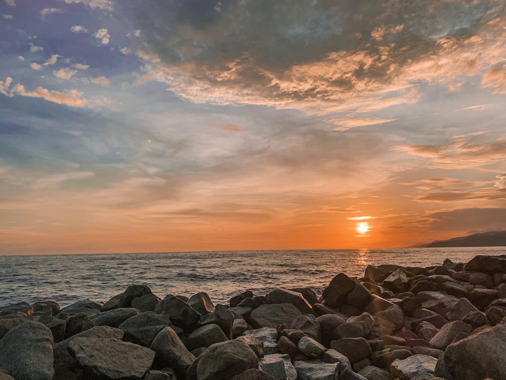 gray rocks near body of water during sunset