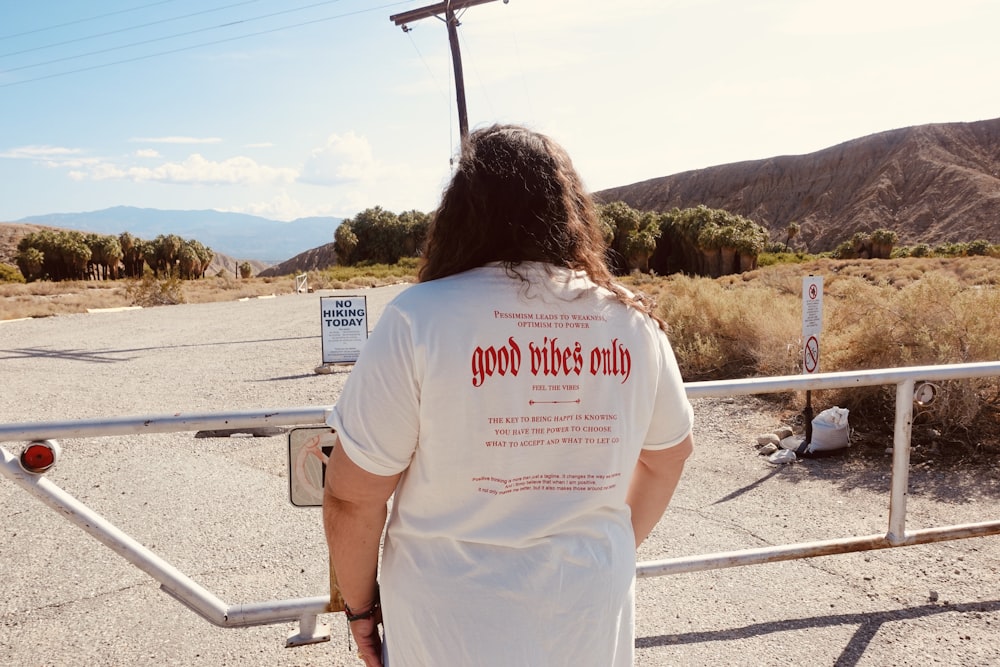 woman in white t-shirt standing near railings during daytime