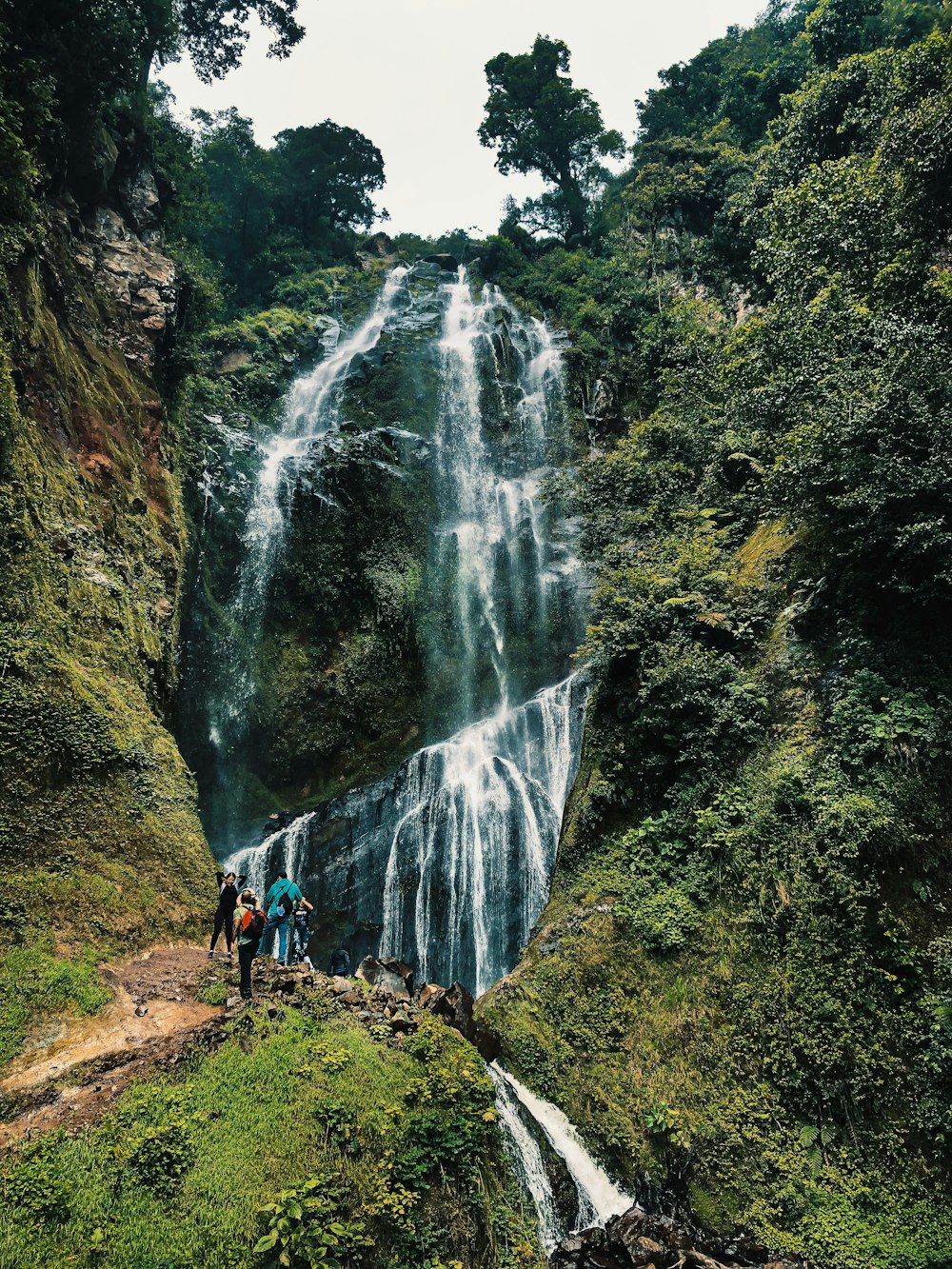 personnes marchant sur le sentier près des chutes d’eau pendant la journée