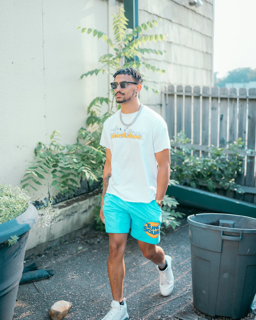 man in white crew neck t-shirt and blue shorts standing on gray concrete floor during
