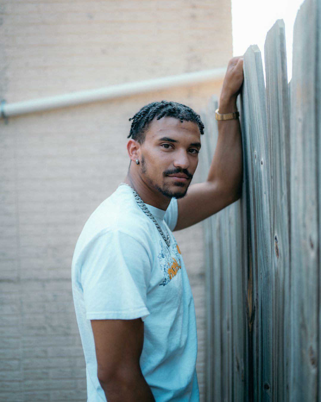 man in white polo shirt standing beside white wall during daytime