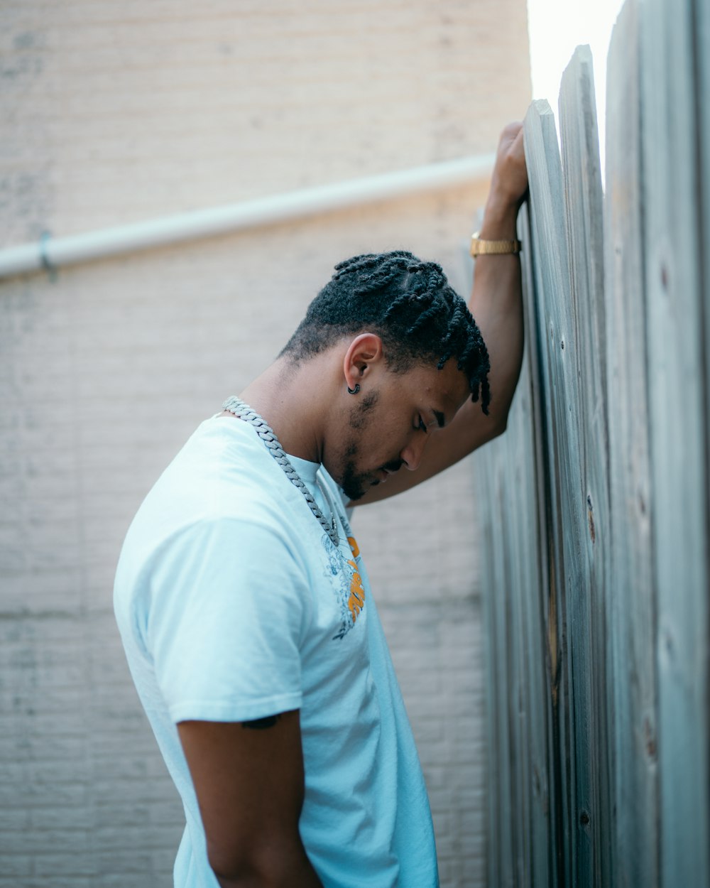 man in white crew neck t-shirt standing near white wall during daytime