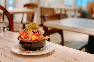 A colorful bowl of nachos made from millets, topped with fresh salsa and herbs.