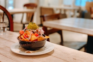 A colorful bowl of nachos made from millets, topped with fresh salsa and herbs.