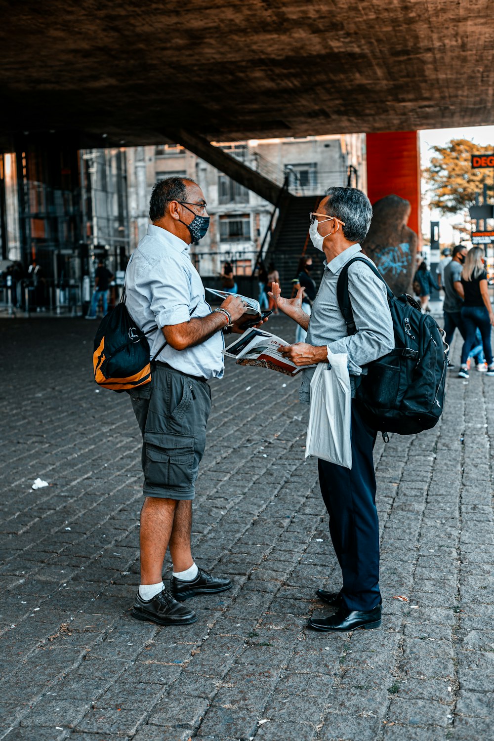 homem na camisa branca e mochila preta segurando o livro