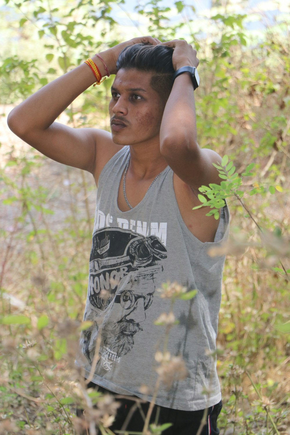 man in gray tank top holding green leaf during daytime