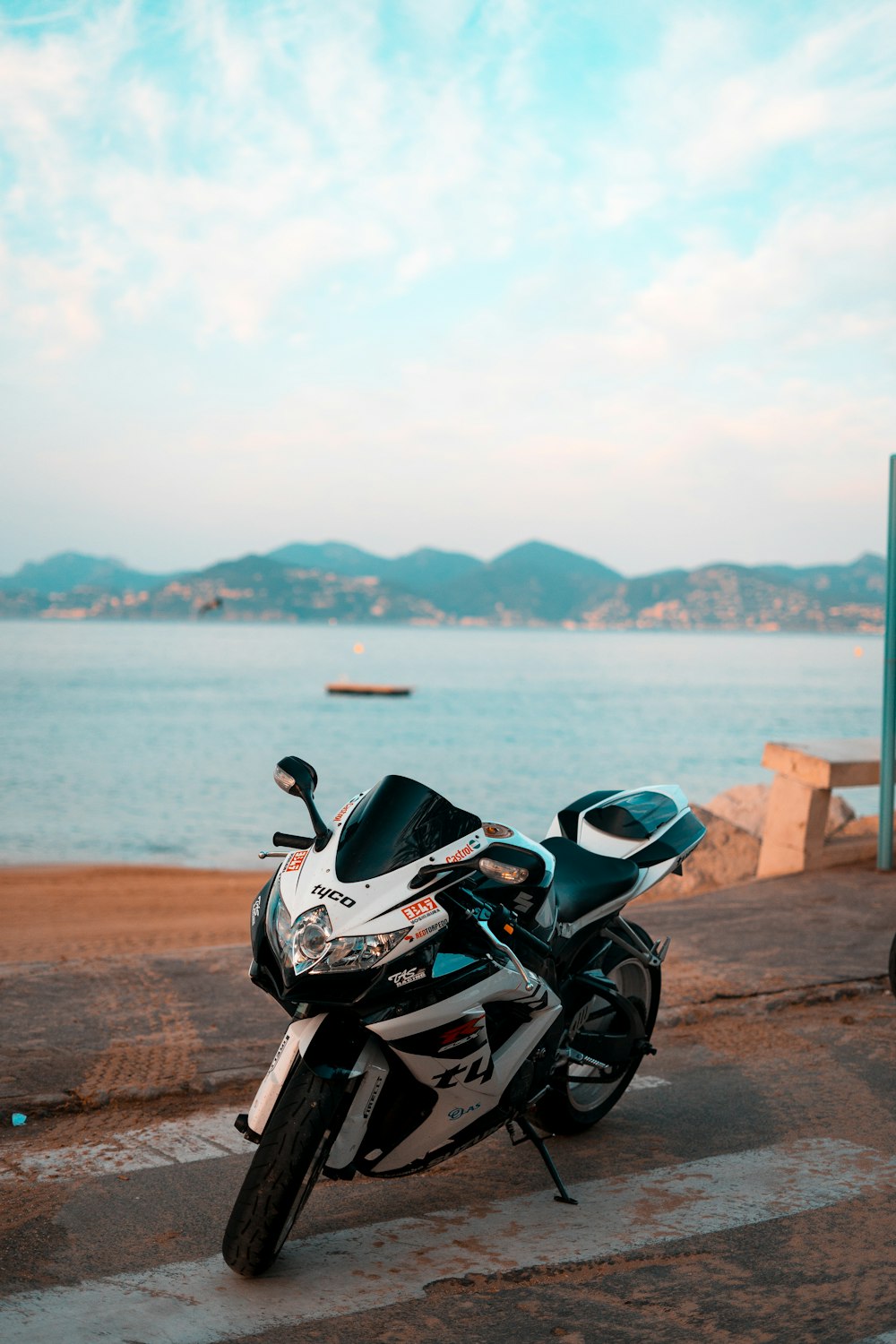 black and white sports bike parked on brown sand near body of water during daytime