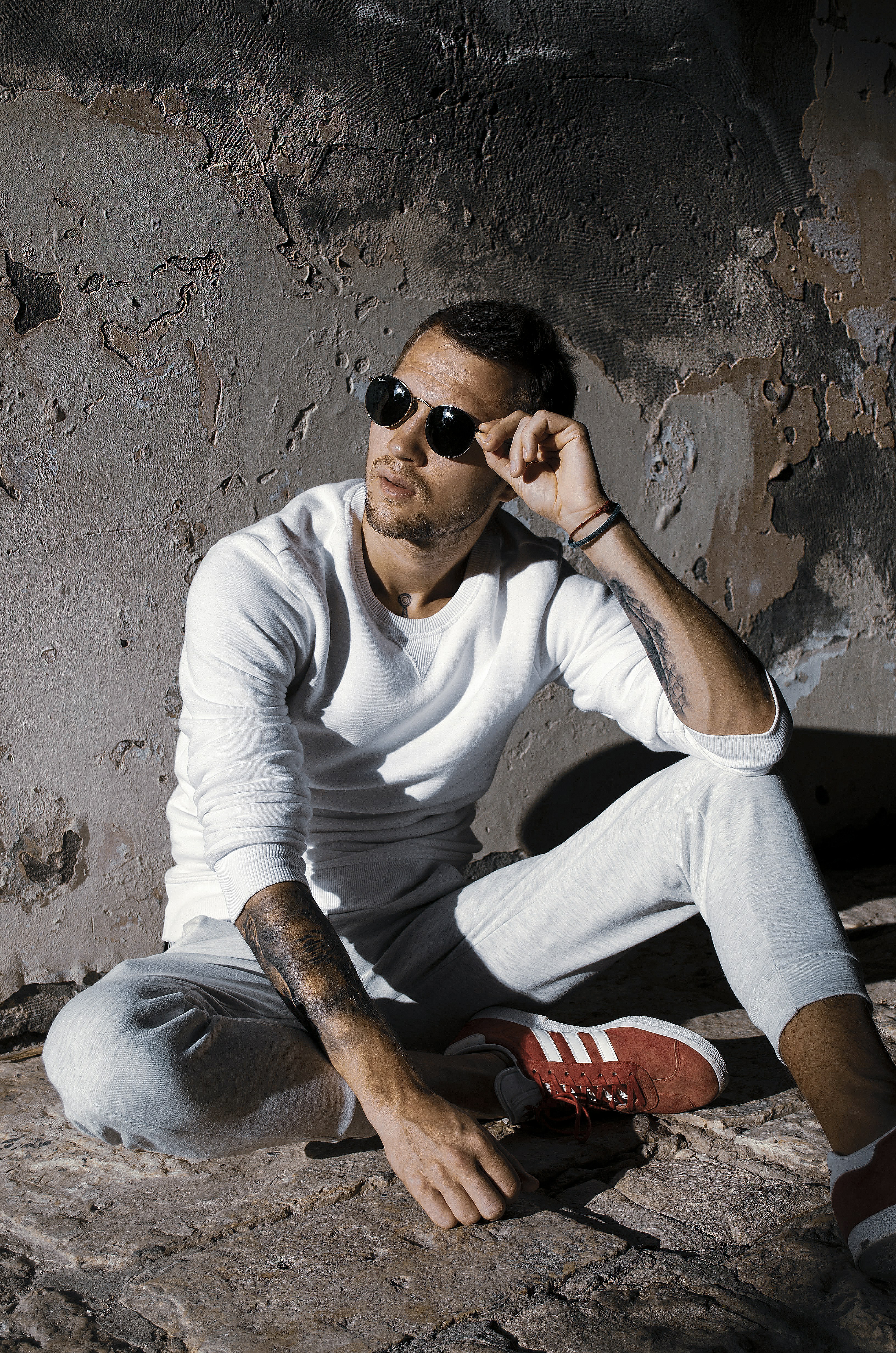 woman in white long sleeve shirt and gray pants wearing black sunglasses sitting on gray concrete