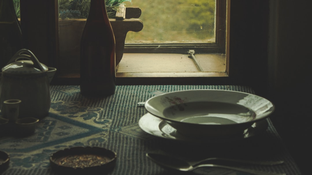 white and blue ceramic round plate beside brown glass bottle