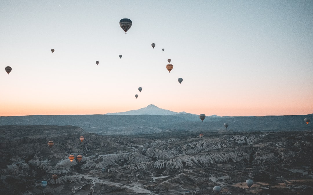 hot air balloons flying over the mountains during sunset