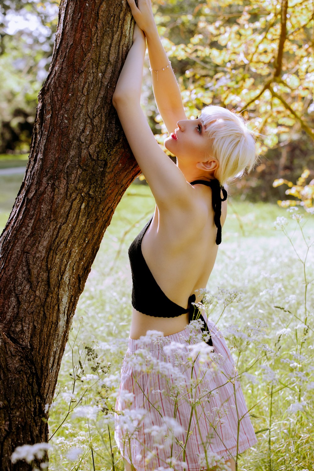 woman in black bikini leaning on brown tree trunk during daytime