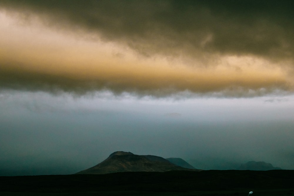 silhouette of mountain under cloudy sky during daytime