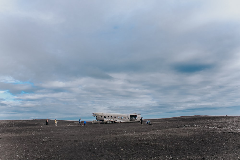 white airplane on brown sand under white clouds during daytime