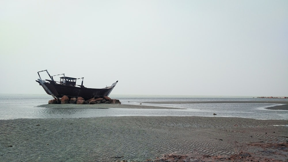black ship on sea shore during daytime