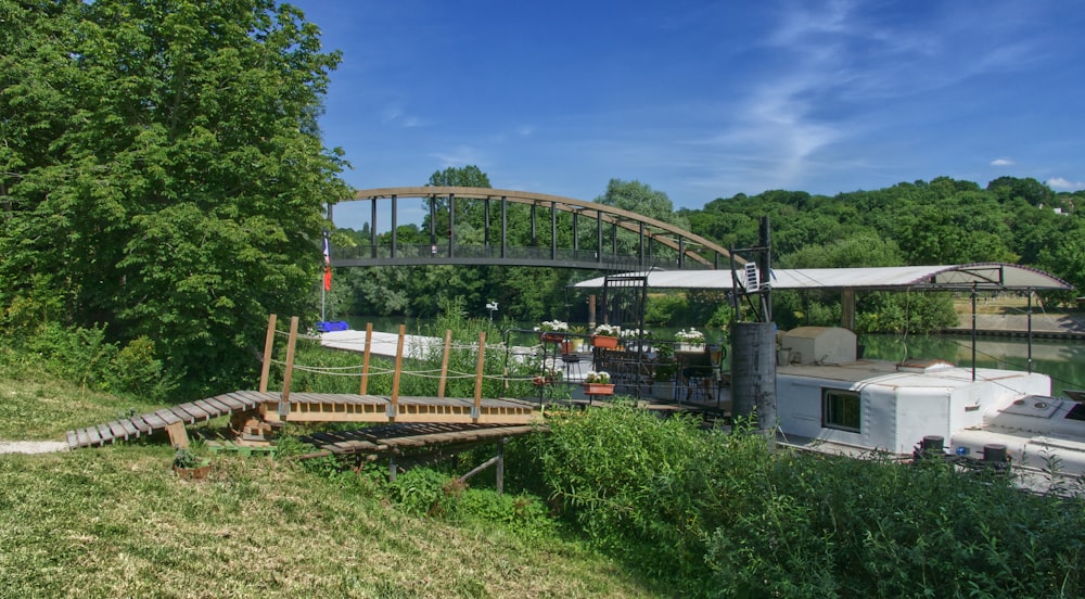 green trees and plants near gray metal bridge under blue sky during daytime