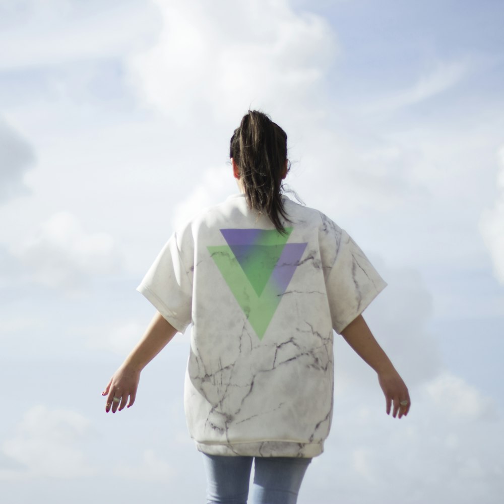 woman in white t-shirt and blue denim jeans standing under white clouds during daytime