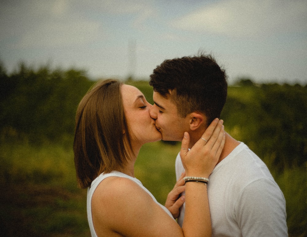 Mann im weißen Tanktop küsst Frau in weißem Tanktop