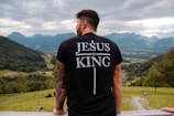 man in black and white crew neck t-shirt standing on green grass field during daytime