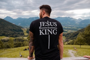 man in black and white crew neck t-shirt standing on green grass field during daytime