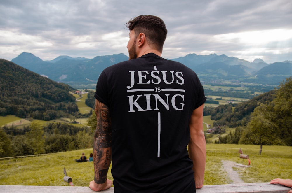 Uomo in t-shirt girocollo in bianco e nero in piedi sul campo in erba verde durante il giorno