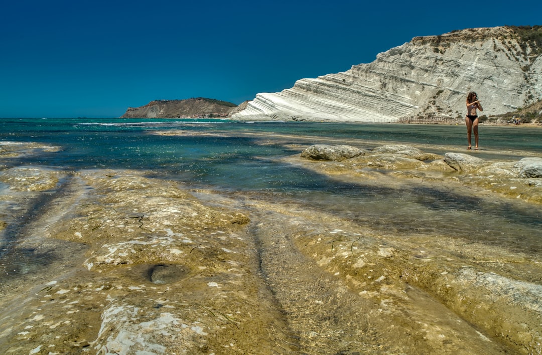 white and brown rocky mountain beside body of water during daytime