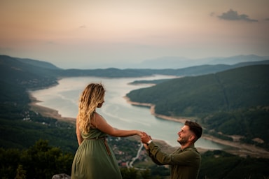 the knee,how to photograph man and woman standing on top of mountain during daytime