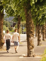 man in white t-shirt walking on sidewalk during daytime