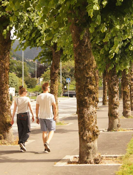 man in white t-shirt walking on sidewalk during daytime