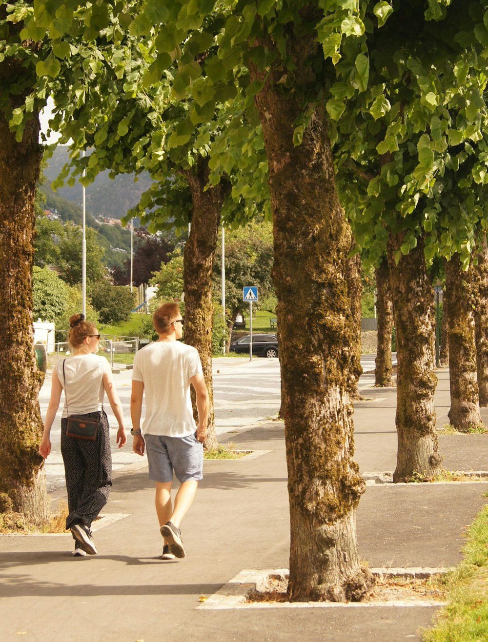 man in white t-shirt walking on sidewalk during daytime