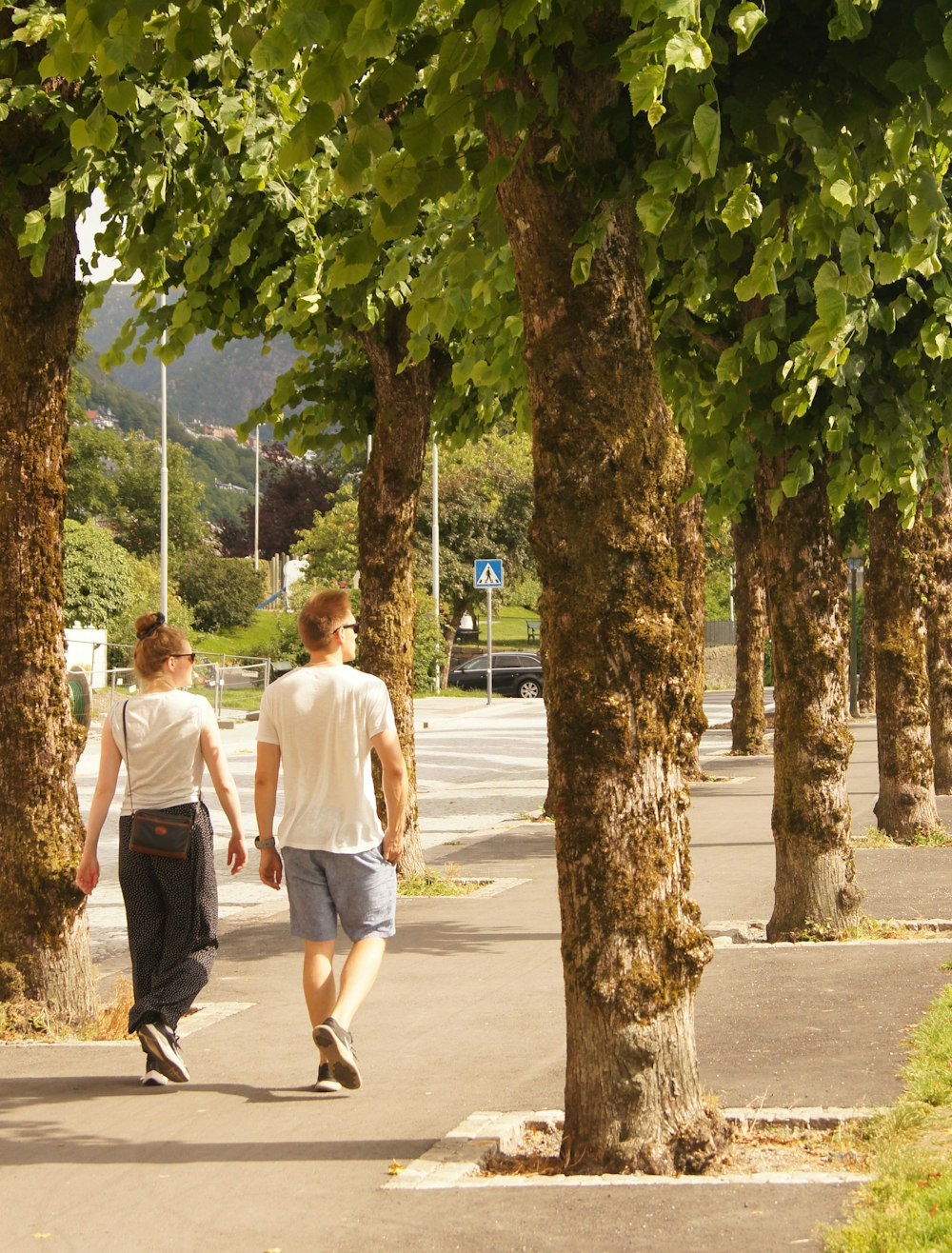 昼間、歩道を歩く白いTシャツの男