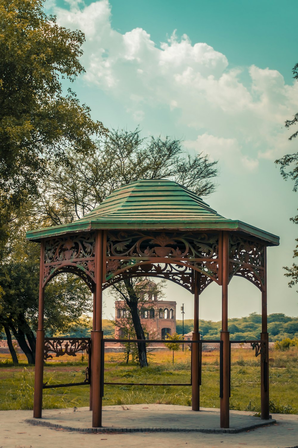 green and brown gazebo surrounded by green trees during daytime