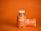 A clear plastic bottle with a white cap contains orange-colored gummies labeled as Jellybee Turmeric & Ginger. The bottle stands on an orange surface against an orange background. Next to it, another bottle lies horizontally, showing a similar label.