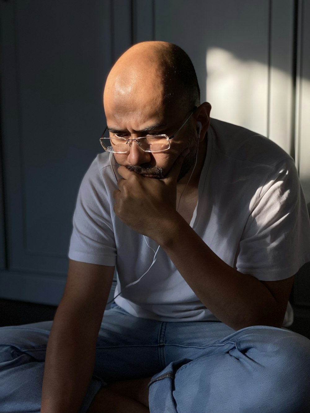 man in white crew neck t-shirt and blue denim jeans sitting on blue chair