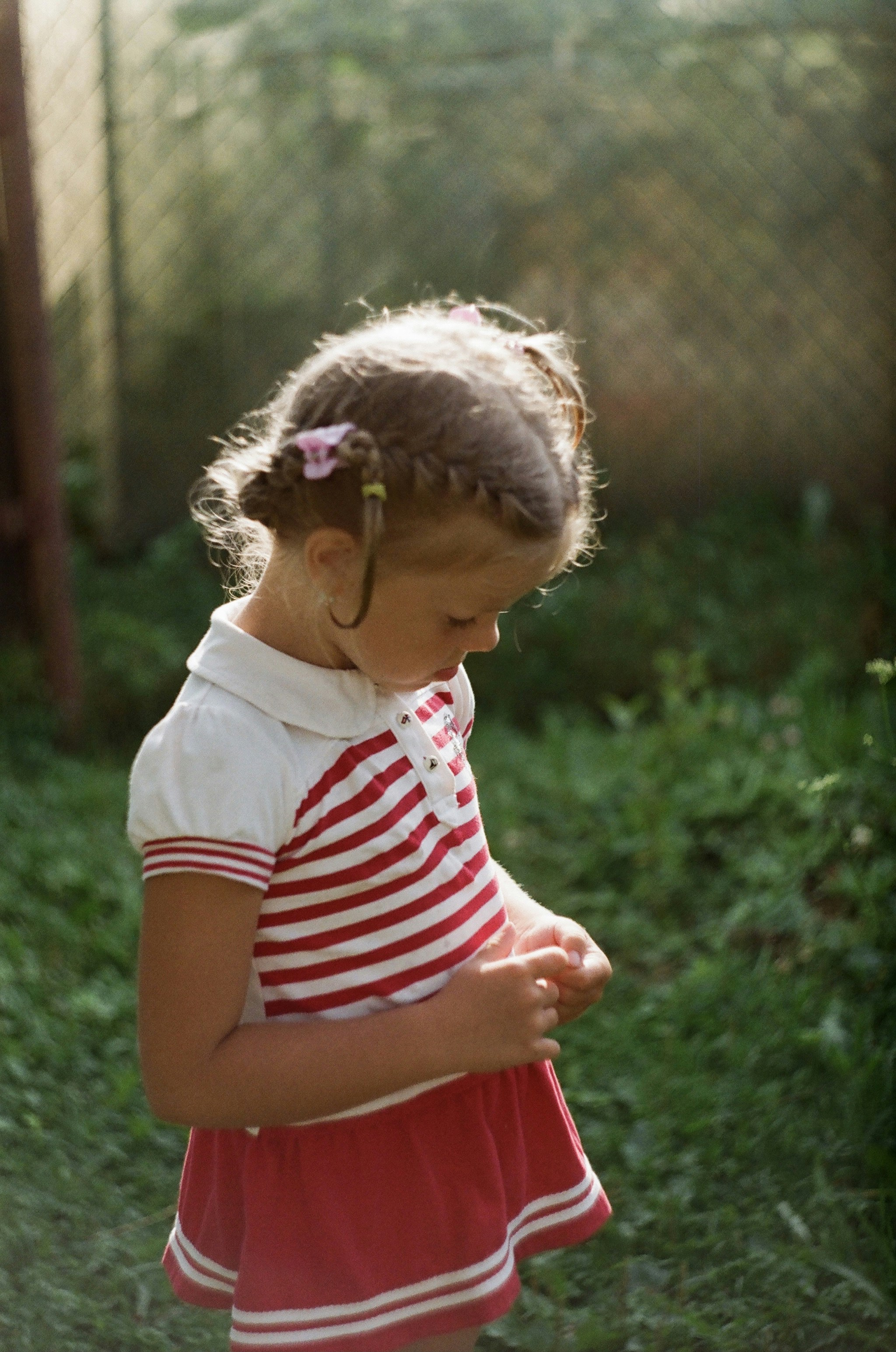 girl in white and red striped shirt standing on green grass field during daytime