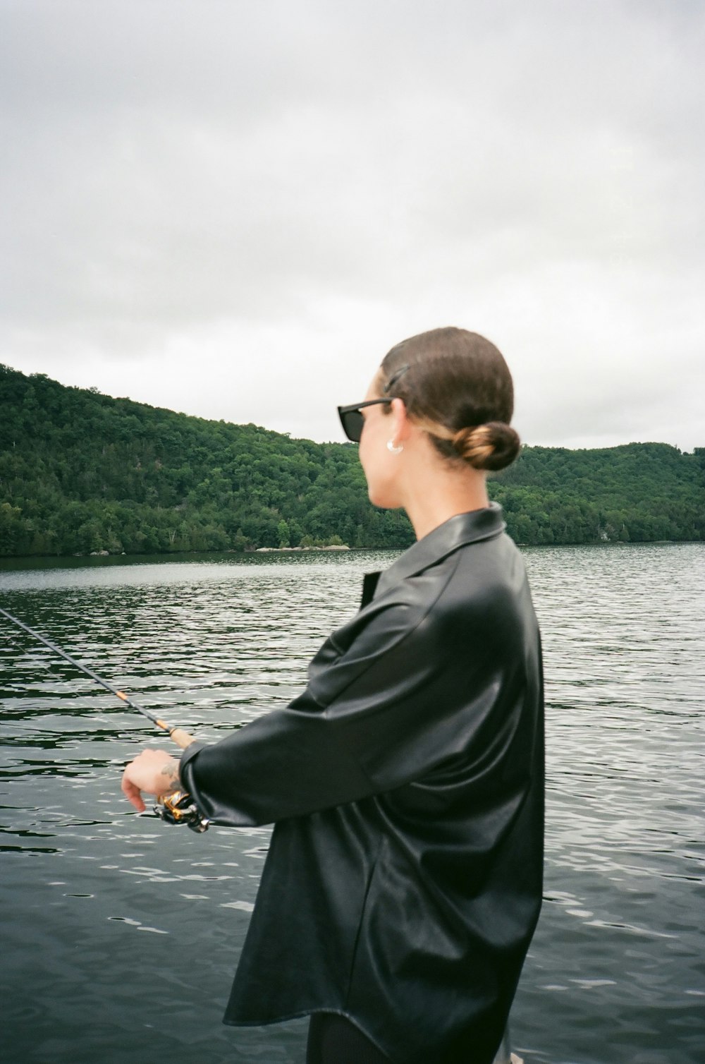 man in black suit jacket holding black fishing rod