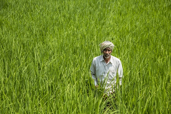 A warm photo of Sajid Hussain and Rukh Mah Akbar standing proudly in their lush farmhouse surrounded by natural food products.