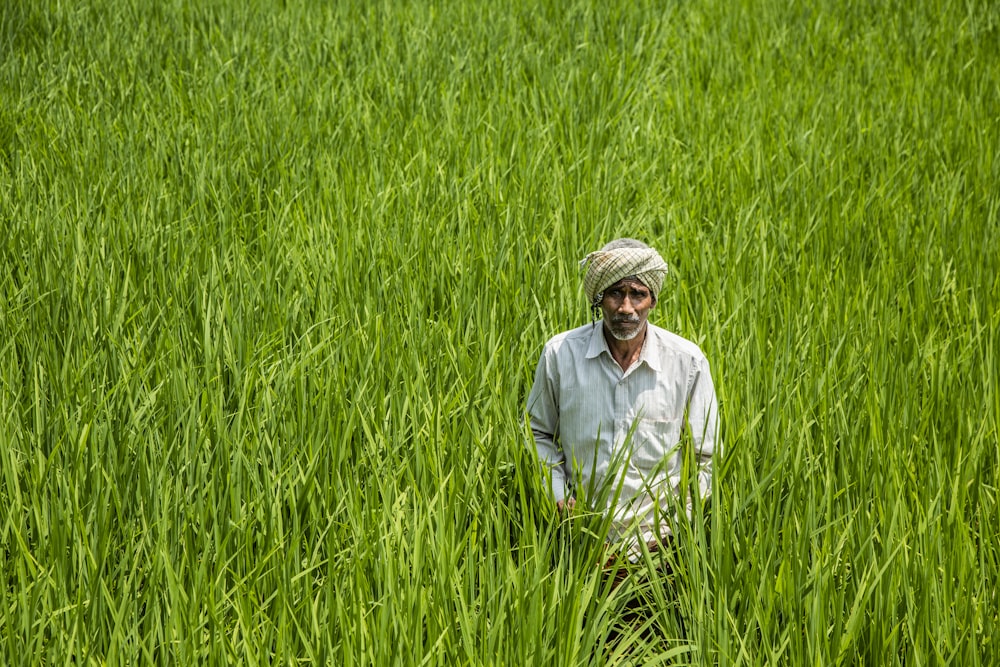 uomo in camicia bianca in piedi sul campo di erba verde durante il giorno
