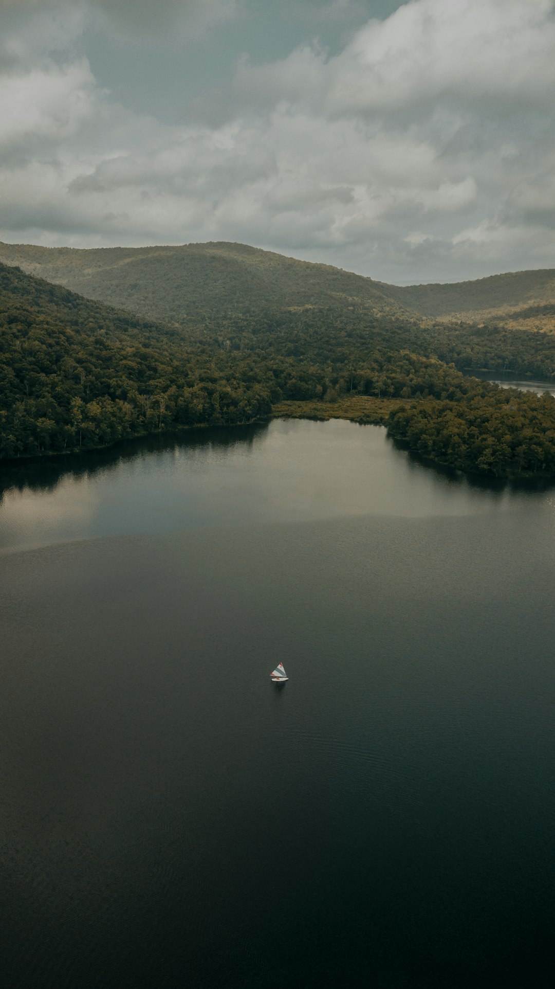 person in white shirt standing on rock in lake during daytime