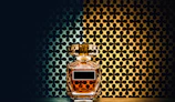 Close-up of a luxurious perfume bottle with amber liquid and golden accents on a dark matte background.