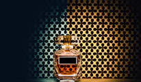 Close-up of a crystal-style perfume bottle with intricate Arabic-inspired patterns reflecting soft gold light.