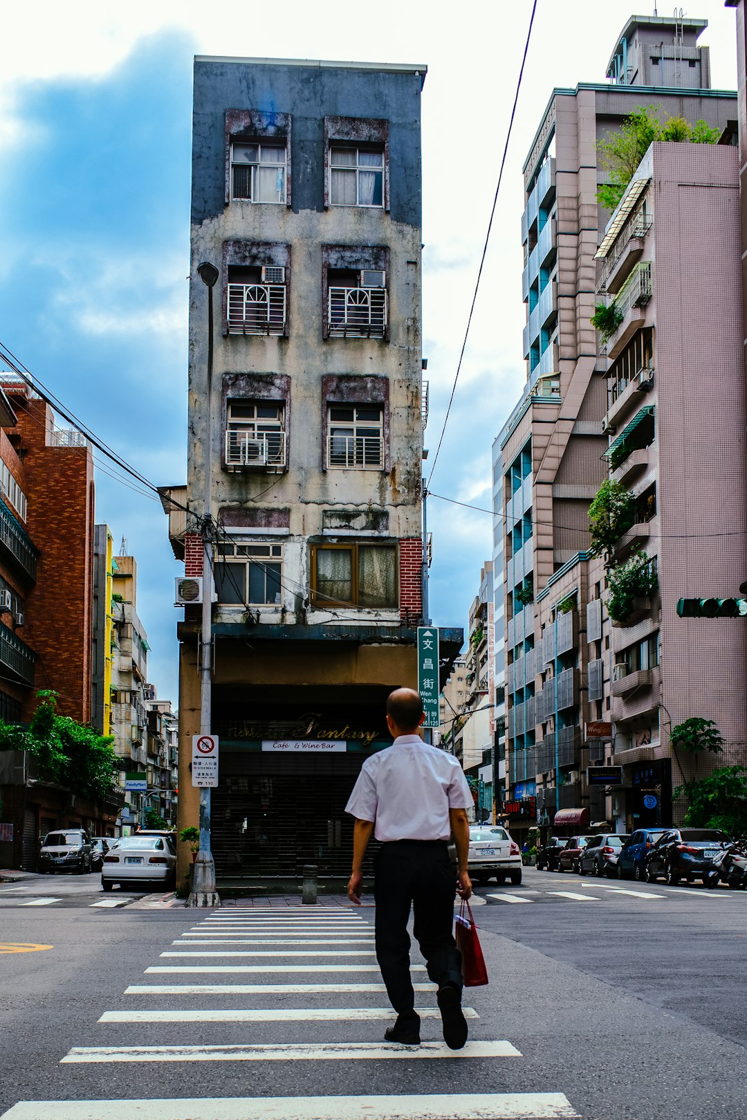 man in white t-shirt and black pants standing on sidewalk during daytime