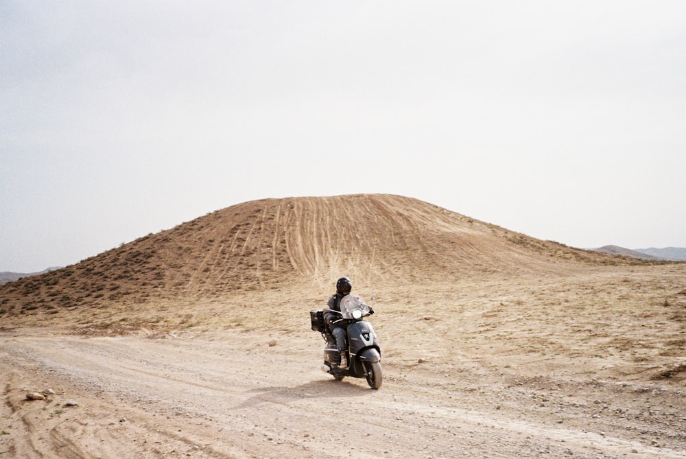 man in black jacket riding motorcycle on brown sand during daytime