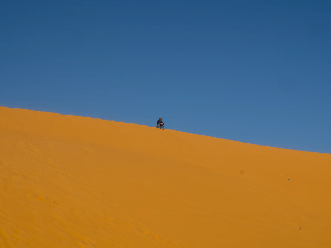 Travellers crossing the dunes with a camel caravan