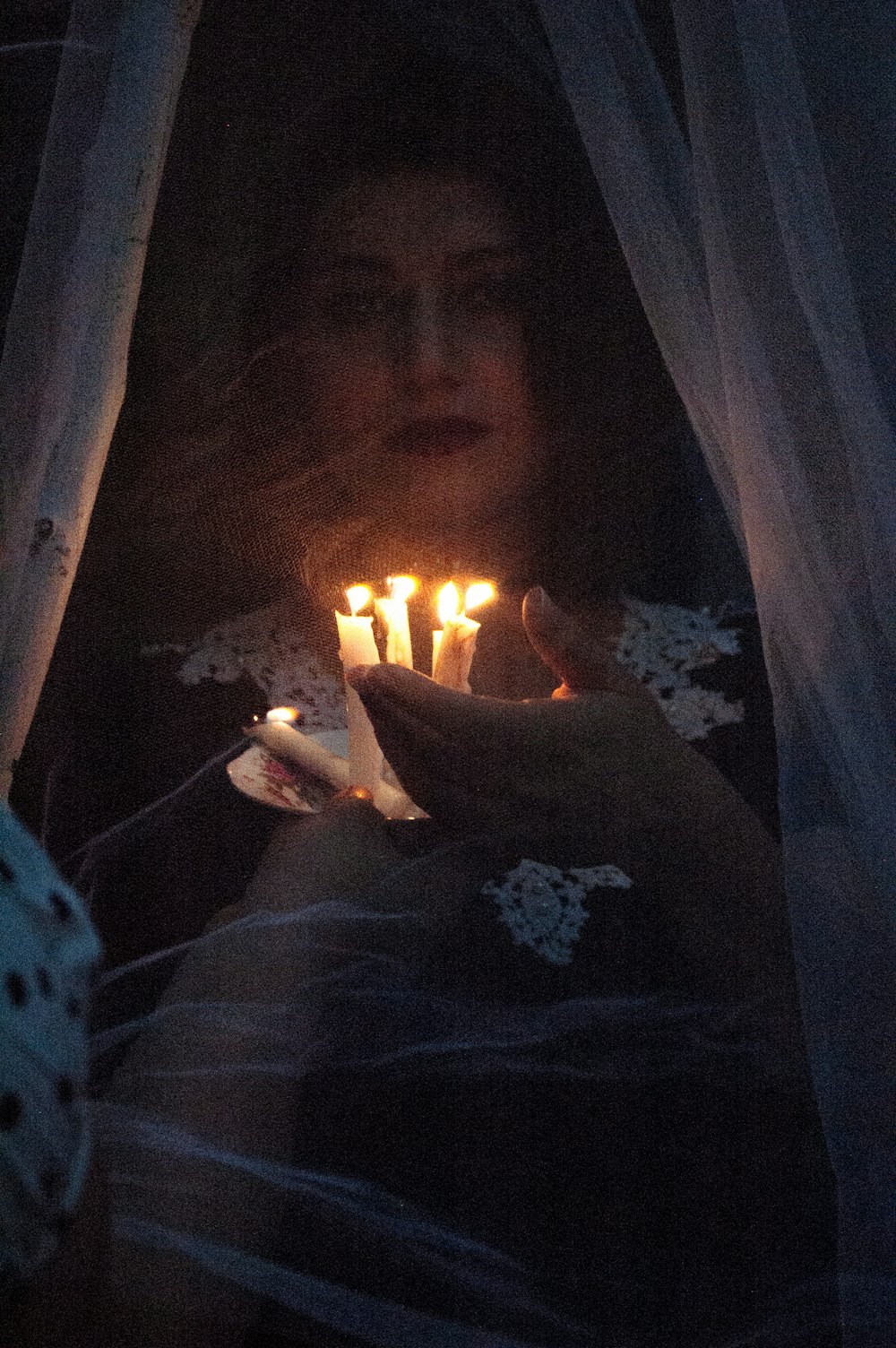 person in white and black polka dot shirt holding lighted candle