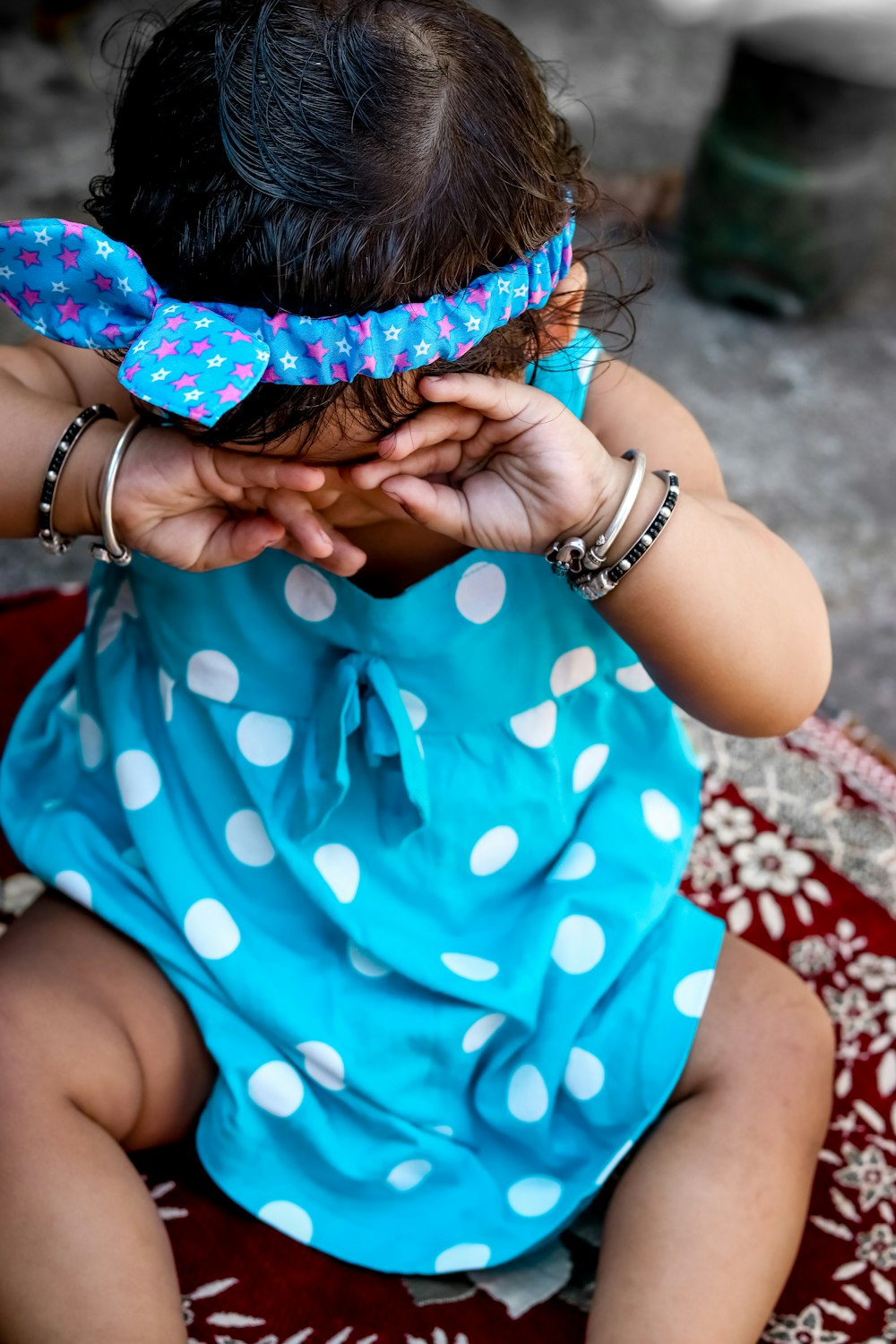 woman in blue and white polka dot shirt covering her face with her hands