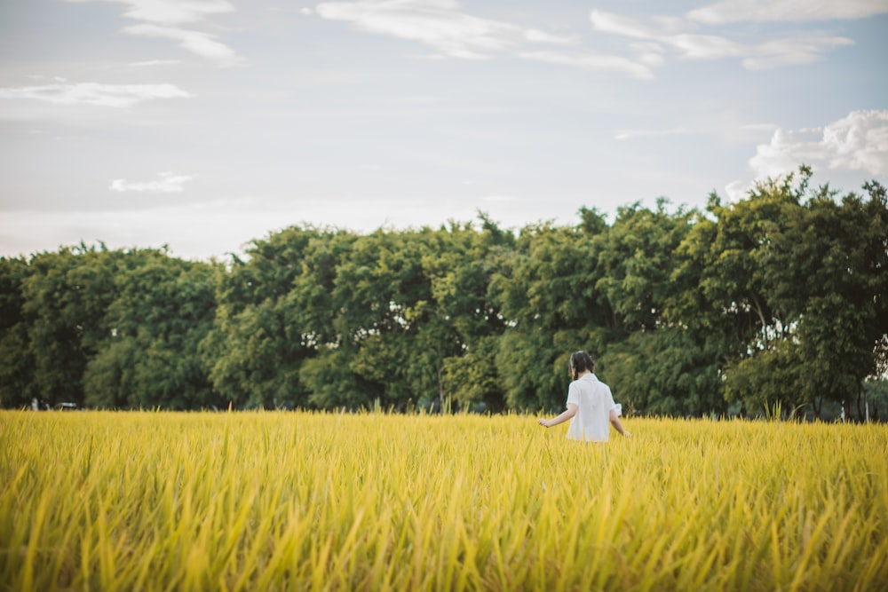 man in white shirt walking on green grass field during daytime