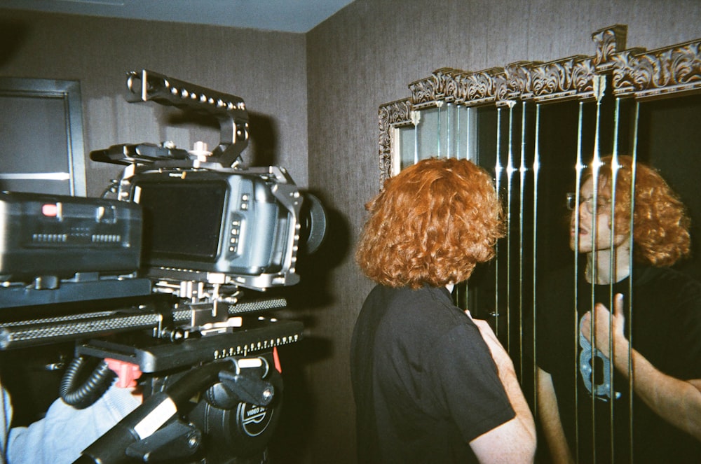 man in black t-shirt standing near black and gray camera