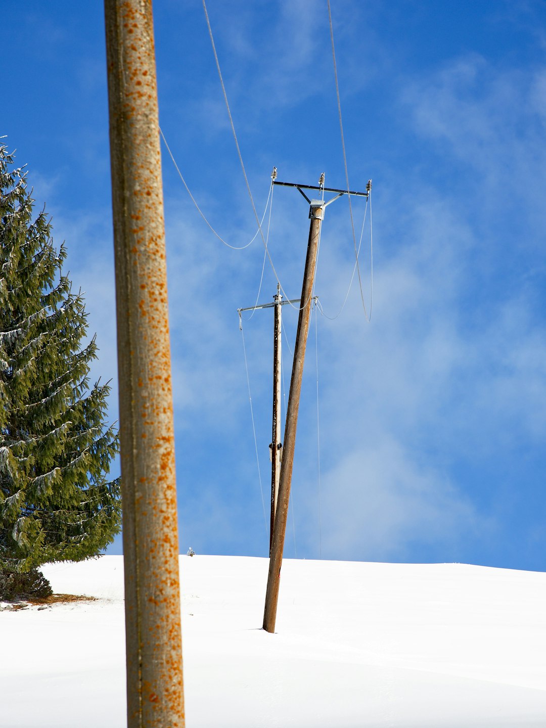 brown wooden electric post on white snow covered ground under blue sky during daytime