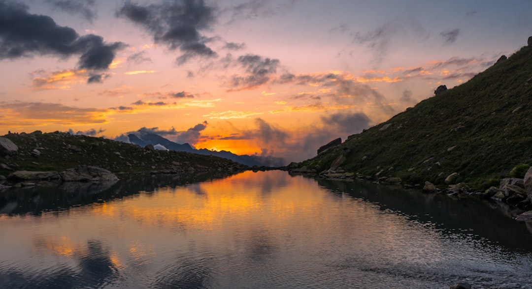 green mountains near body of water under cloudy sky during daytime