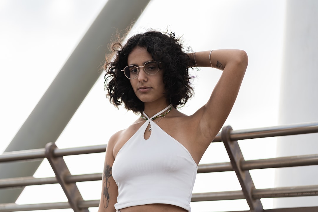 woman in white halter top and white panty standing near white metal railings during daytime